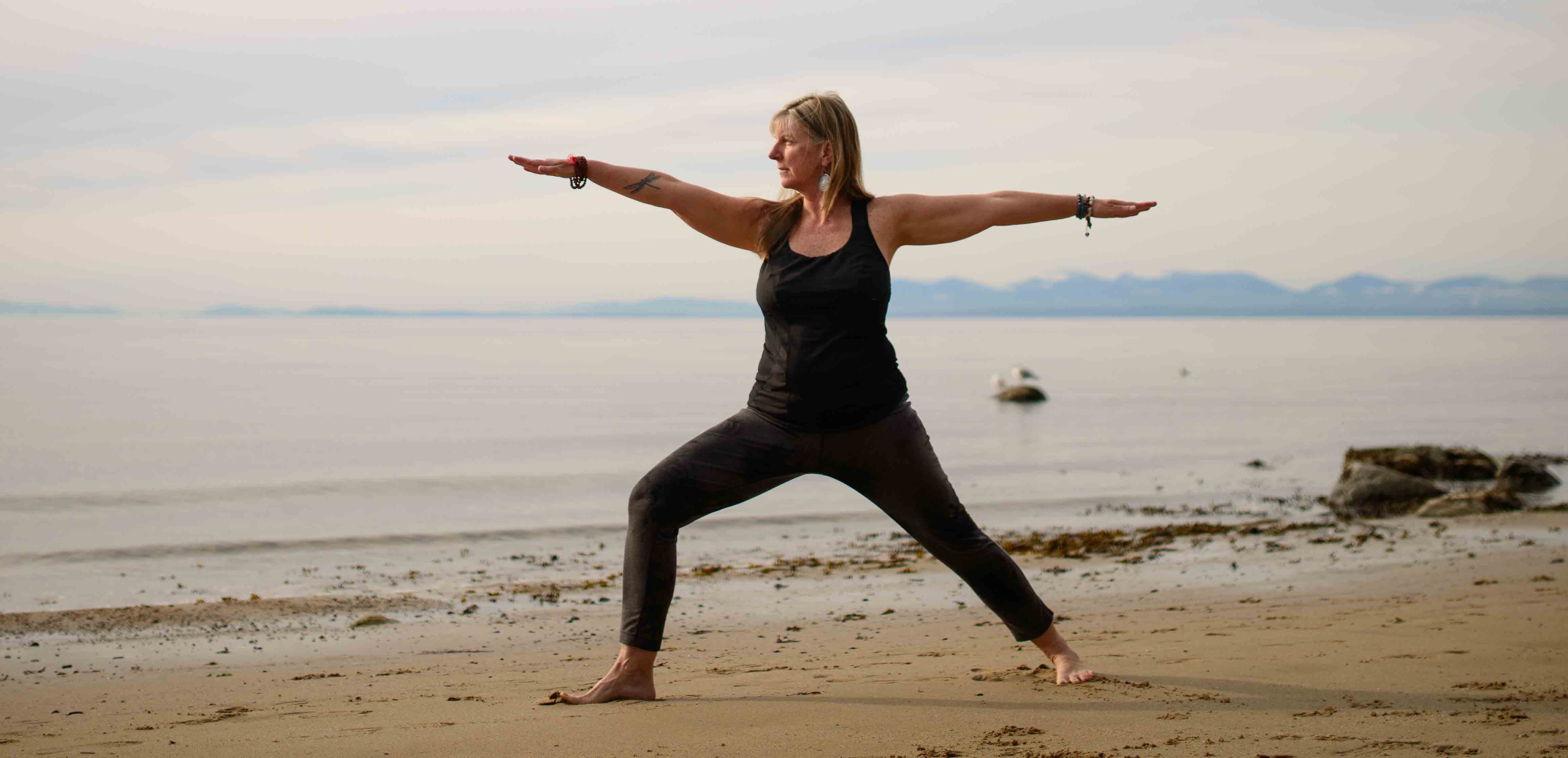 Marney Hasu Coulter performing a yoga pose on the beach